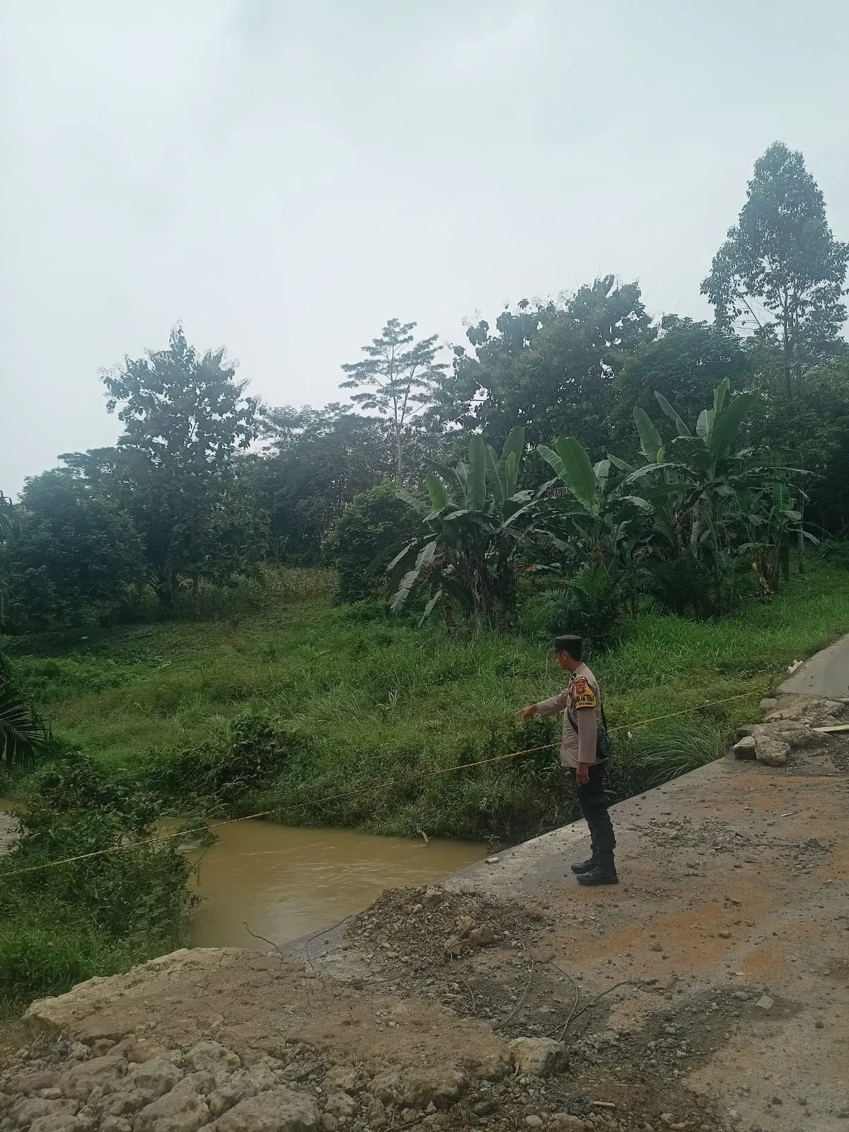 Petugas Polsek Talang Ubi memantau kondisi banjir di jalan desa.